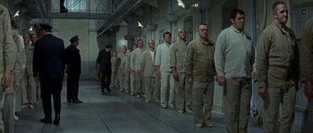 Movie still from “The Brain” (1969), directed by Gérard Oury – A group of men in tan and white uniforms standing in a line; Wide shot, High angle