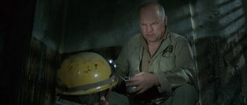 Movie still from “The Brain” (1969), directed by Gérard Oury – An older man is holding a cup and looking at a man wearing a hard hat; Medium shot, High angle