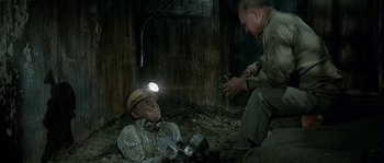 Movie still from “The Brain” (1969), directed by Gérard Oury – Two men in a coal mine one of which is holding a flashlight; Medium shot, High angle