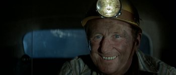 Movie still from “The Brain” (1969), directed by Gérard Oury – An older man wearing a hard hat with a light on his head; Close Up shot, Low angle
