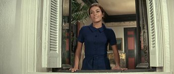 Movie still from “The Brain” (1969), directed by Gérard Oury – A woman standing in front of an open window; Medium shot, Low angle