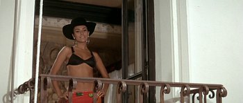 Movie still from “The Brain” (1969), directed by Gérard Oury – A woman in a black bra and a black cowboy hat; Medium shot, Low angle