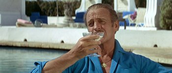 Movie still from “The Brain” (1969), directed by Gérard Oury – A man in a blue shirt is holding a drink; Close Up shot, Low angle