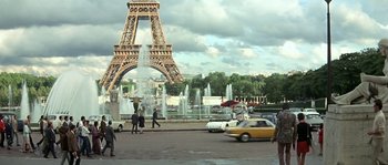 Movie still from “The Brain” (1969), directed by Gérard Oury – People are walking near a fountain near the eiffel tower in paris; Extreme Wide shot, High angle