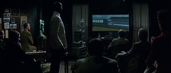 Movie still from “The Brain” (1969), directed by Gérard Oury – A group of people sitting around a living room watching a movie; Wide shot, Over the shoulder angle