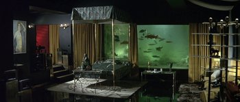 Movie still from “The Brain” (1969), directed by Gérard Oury – A bed room with a fish tank in the background; Extreme Wide shot, High angle