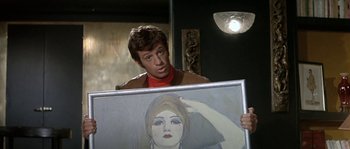Movie still from “The Brain” (1969), directed by Gérard Oury – A man holding a painting in front of a mirror; Medium shot, Over the shoulder angle