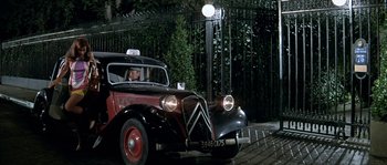 Movie still from “The Brain” (1969), directed by Gérard Oury – An old car is parked on the side of the road; Wide shot, Low angle