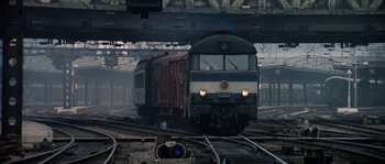 Movie still from “The Brain” (1969), directed by Gérard Oury – A train on a train track near a train station; Extreme Wide shot, Low angle