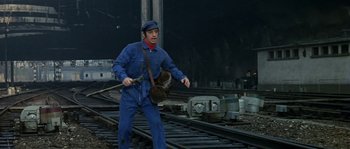 Movie still from “The Brain” (1969), directed by Gérard Oury – A man in blue overalls and a blue hat holding a cat; Wide shot, High angle