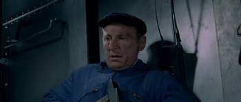 Movie still from “The Brain” (1969), directed by Gérard Oury – An older man wearing a blue jacket and a hat; Close Up shot, High angle