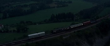 Movie still from “The Brain” (1969), directed by Gérard Oury – A train traveling down the train tracks near a lush green field; Extreme Wide shot, High angle