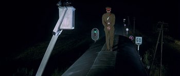 Movie still from “The Brain” (1969), directed by Gérard Oury – A man standing on the side of a road at night; Wide shot, Low angle