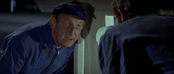 Movie still from “The Brain” (1969), directed by Gérard Oury – An older man wearing a blue hat looking into a mirror; Close Up shot, Over the shoulder angle