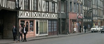 Movie still from “The Brain” (1969), directed by Gérard Oury – An image of a building that is on the side of the street; Extreme Wide shot, High angle