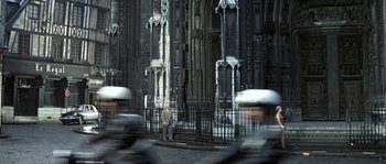 Movie still from “The Brain” (1969), directed by Gérard Oury – A man standing in front of an old building; Extreme Wide shot, Low angle