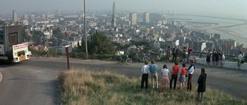 Movie still from “The Brain” (1969), directed by Gérard Oury – A group of people standing on top of a grass covered hill; Extreme Wide shot, High angle
