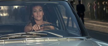 Movie still from “The Brain” (1969), directed by Gérard Oury – A woman sitting in the driver's seat of a car; Close Up shot, High angle