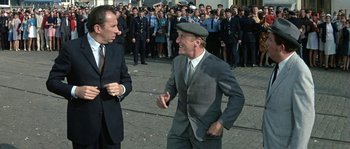 Movie still from “The Brain” (1969), directed by Gérard Oury – A man in a suit and hat talking to another man in a suit and hat; Medium shot, Over the shoulder angle