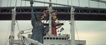 Movie still from “The Brain” (1969), directed by Gérard Oury – The statue of liberty stands in front of a cruise ship; Extreme Wide shot, Low angle