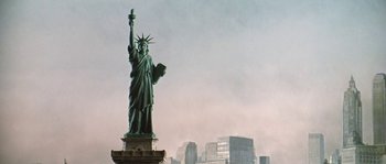 Movie still from “The Brain” (1969), directed by Gérard Oury – The statue of liberty stands in front of a city skyline; Extreme Wide shot, Low angle