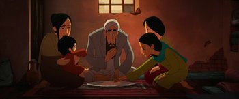 Movie still from “The Breadwinner” (2017), directed by Nora Twomey – A group of people sitting around a plate of food; Wide shot, Over the shoulder angle