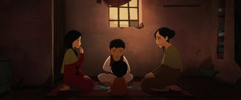Movie still from “The Breadwinner” (2017), directed by Nora Twomey – A group of people sitting on the ground in front of a window; Wide shot, High angle