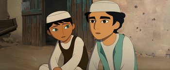 Movie still from “The Breadwinner” (2017), directed by Nora Twomey – Two young men wearing white hats are sitting next to each other; Close Up shot, Over the shoulder angle