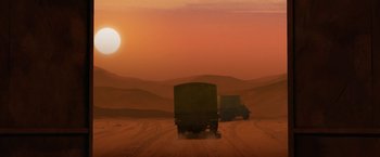 Movie still from “The Breadwinner” (2017), directed by Nora Twomey – A couple of trucks driving down a dirt road in the middle of the desert; Extreme Wide shot, Low angle