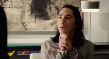 Movie still from “The Break-Up” (2006), directed by Peyton Reed – A man with long black hair sitting in front of a painting; Close Up shot, Over the shoulder angle