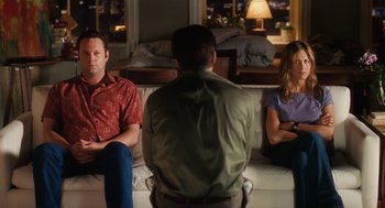 Movie still from “The Break-Up” (2006), directed by Peyton Reed – Two men and a woman sitting on a white couch; Medium shot, Over the shoulder angle