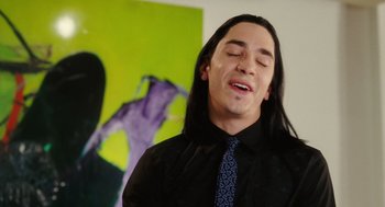A man with long black hair wearing a black shirt and a tie