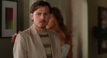 Movie still from “The Break-Up” (2006), directed by Peyton Reed – A man in a jacket and striped shirt looking at the camera; Close Up shot, Over the shoulder angle
