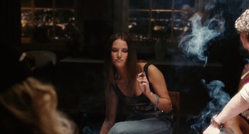 Movie still from “The Break-Up” (2006), directed by Peyton Reed – A woman smoking a cigarette while sitting on a chair; Medium shot, Over the shoulder angle