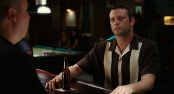 Movie still from “The Break-Up” (2006), directed by Peyton Reed – A man sitting at a table with a bottle of beer in front of a pool table; Close Up shot, Over the shoulder angle