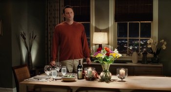 Movie still from “The Break-Up” (2006), directed by Peyton Reed – A man standing in front of a dining table; Medium shot, Over the shoulder angle