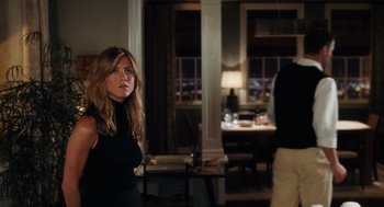 Movie still from “The Break-Up” (2006), directed by Peyton Reed – A woman standing in a living room next to a table; Medium shot, Over the shoulder angle