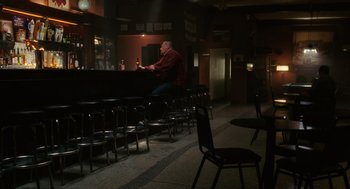 Movie still from “The Break-Up” (2006), directed by Peyton Reed – A man sitting at a bar with a bottle of beer; Wide shot, High angle