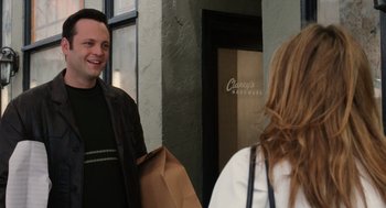 Movie still from “The Break-Up” (2006), directed by Peyton Reed – A man and a woman standing next to each other holding brown bags; Medium shot, Over the shoulder angle