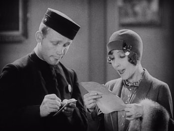 Movie still from “The Broadway Melody” (1929), directed by Harry Beaumont – An old photo of a man and a woman looking at a piece of paper; Medium shot, High angle