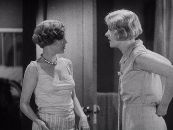 Two women talking to each other in front of a mirror