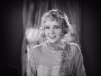Movie still from “The Broadway Melody” (1929), directed by Harry Beaumont – An old black and white photo of a woman smiling; Close Up shot, High angle