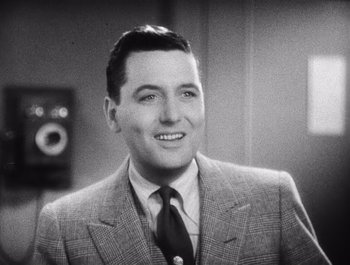 Movie still from “The Broadway Melody” (1929), directed by Harry Beaumont – An older man in a suit smiling for the camera; Close Up shot, Low angle