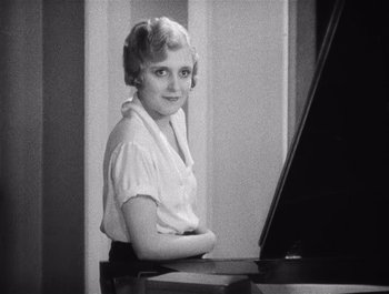 Movie still from “The Broadway Melody” (1929), directed by Harry Beaumont – An old photo of a woman sitting at a piano; Medium shot, High angle