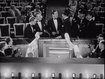 Movie still from “The Broadway Melody” (1929), directed by Harry Beaumont – A black and white photo of a group of men in tuxedos; Wide shot, High angle
