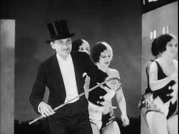 Movie still from “The Broadway Melody” (1929), directed by Harry Beaumont – A man in a top hat holding a flute; Medium shot, Low angle