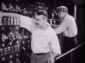 Movie still from “The Broadway Melody” (1929), directed by Harry Beaumont – Two men working in an electrical plant; Medium shot, Low angle