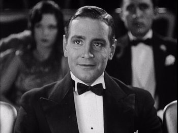 Movie still from “The Broadway Melody” (1929), directed by Harry Beaumont – A black and white photo of a man in a tuxedo; Close Up shot, Low angle
