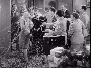 Movie still from “The Broadway Melody” (1929), directed by Harry Beaumont – A group of people standing in a room with confetti; Wide shot, High angle