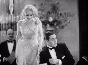 Movie still from “The Broadway Melody” (1929), directed by Harry Beaumont – A man and a woman in formal wear in a black and white photo; Medium shot, Over the shoulder angle